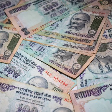 Masada birleşik 100 rupi, dönen masada Hindistan parası var. Eski Hint Para Birimi notları masanın üzerinde, Hint Para Birimi masanın üstünde.