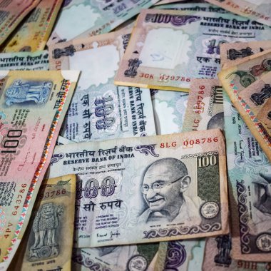 Masada birleşik 100 rupi, dönen masada Hindistan parası var. Eski Hint Para Birimi notları masanın üzerinde, Hint Para Birimi masanın üstünde.