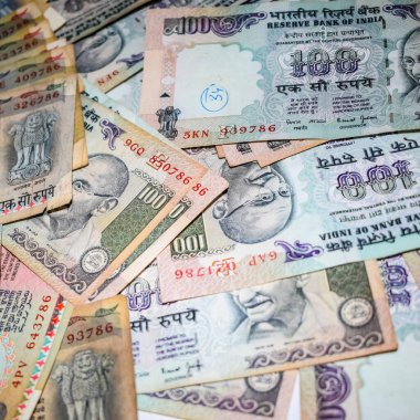 Masada birleşik 100 rupi, dönen masada Hindistan parası var. Eski Hint Para Birimi notları masanın üzerinde, Hint Para Birimi masanın üstünde.