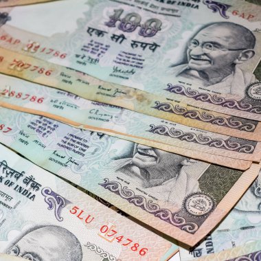 Masada birleşik 100 rupi, dönen masada Hindistan parası var. Eski Hint Para Birimi notları masanın üzerinde, Hint Para Birimi masanın üstünde.