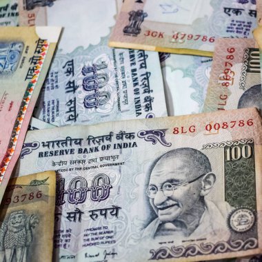 Masada birleşik 100 rupi, dönen masada Hindistan parası var. Eski Hint Para Birimi notları masanın üzerinde, Hint Para Birimi masanın üstünde.