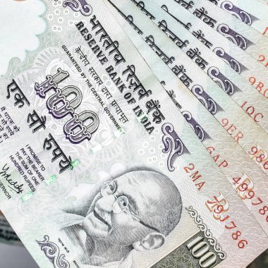 Masada birleşik 100 rupi, dönen masada Hindistan parası var. Eski Hint Para Birimi notları masanın üzerinde, Hint Para Birimi masanın üstünde.