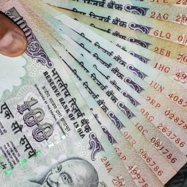 Masada birleşik 100 rupi, dönen masada Hindistan parası var. Eski Hint Para Birimi notları masanın üzerinde, Hint Para Birimi masanın üstünde.