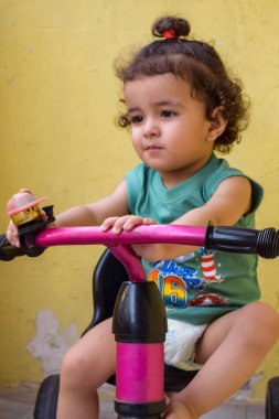 Şirin küçük çocuk Shivaay yaz zamanı balkonda bisiklet sürüyor, gün ışığında tatlı küçük çocuk fotoğraf çekiyor, küçük çocuk fotoğraf çekimi sırasında bisiklet sürmekten hoşlanıyor.