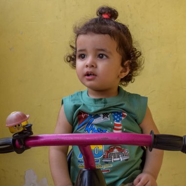 Şirin küçük çocuk Shivaay yaz zamanı balkonda bisiklet sürüyor, gün ışığında tatlı küçük çocuk fotoğraf çekiyor, küçük çocuk fotoğraf çekimi sırasında bisiklet sürmekten hoşlanıyor.