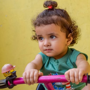 Şirin küçük çocuk Shivaay yaz zamanı balkonda bisiklet sürüyor, gün ışığında tatlı küçük çocuk fotoğraf çekiyor, küçük çocuk fotoğraf çekimi sırasında bisiklet sürmekten hoşlanıyor.