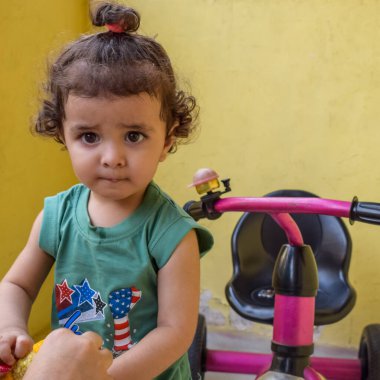 Şirin küçük çocuk Shivaay yaz zamanı balkonda bisiklet sürüyor, gün ışığında tatlı küçük çocuk fotoğraf çekiyor, küçük çocuk fotoğraf çekimi sırasında bisiklet sürmekten hoşlanıyor.