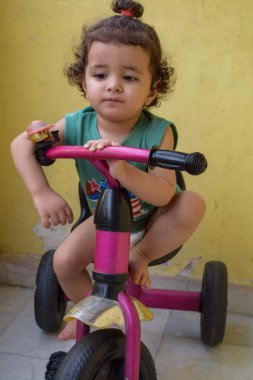 Şirin küçük çocuk Shivaay yaz zamanı balkonda bisiklet sürüyor, gün ışığında tatlı küçük çocuk fotoğraf çekiyor, küçük çocuk fotoğraf çekimi sırasında bisiklet sürmekten hoşlanıyor.