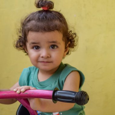 Şirin küçük çocuk Shivaay yaz zamanı balkonda bisiklet sürüyor, gün ışığında tatlı küçük çocuk fotoğraf çekiyor, küçük çocuk fotoğraf çekimi sırasında bisiklet sürmekten hoşlanıyor.