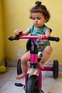 Şirin küçük çocuk Shivaay yaz zamanı balkonda bisiklet sürüyor, gün ışığında tatlı küçük çocuk fotoğraf çekiyor, küçük çocuk fotoğraf çekimi sırasında bisiklet sürmekten hoşlanıyor.