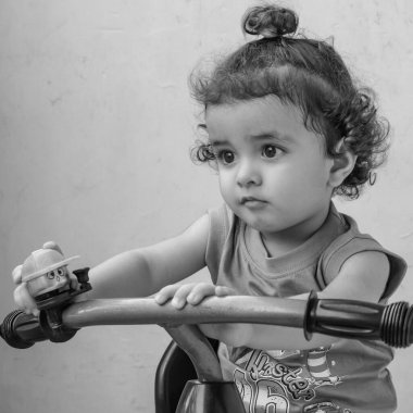 Şirin küçük çocuk Shivaay yaz zamanı balkonda bisiklet sürüyor, gün ışığında tatlı küçük çocuk fotoşopunu çekiyor, küçük çocuk fotoğraf çekimi sırasında evde bisiklet sürmekten hoşlanıyor.