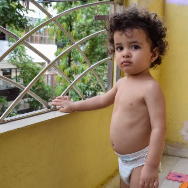 Şirin küçük çocuk Shivaay yaz zamanı evde balkonda, tatlı küçük çocuk gün ışığında fotoşop, küçük çocuk fotoğraf çekimi sırasında evde eğleniyor.