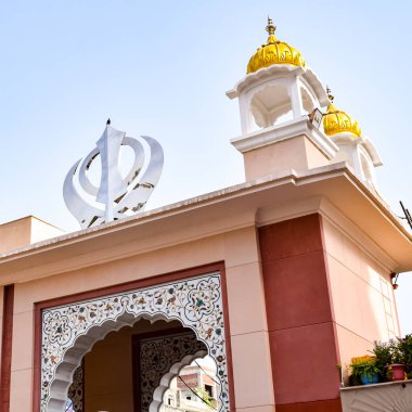 Gurudwara girişindeki Khanda Sikh kutsal dini sembolü parlak mavi gökyüzü görüntüsü, Chandni Chowk 'taki Eski Delhi' deki Kızıl Kale 'nin karşısındaki Sis Ganj Sahib Gurudwara' da çekildi.