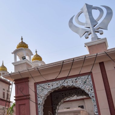 Gurudwara girişindeki Khanda Sikh kutsal dini sembolü parlak mavi gökyüzü görüntüsü, Chandni Chowk 'taki Eski Delhi' deki Kızıl Kale 'nin karşısındaki Sis Ganj Sahib Gurudwara' da çekildi.