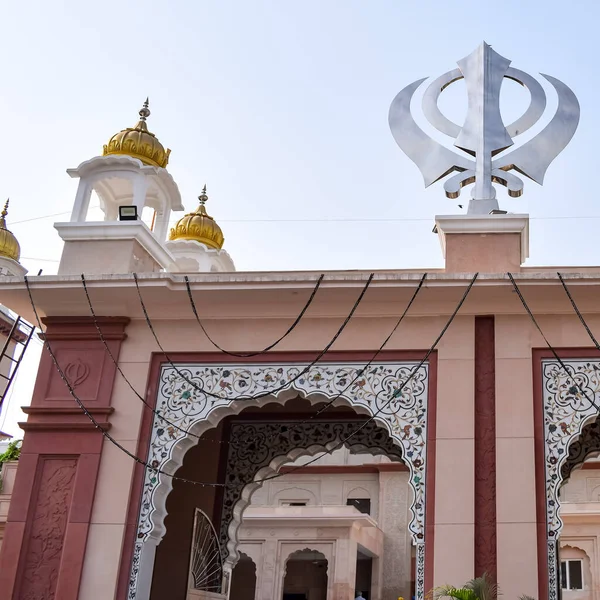 Gurudwara girişindeki Khanda Sikh kutsal dini sembolü parlak mavi gökyüzü görüntüsü, Chandni Chowk 'taki Eski Delhi' deki Kızıl Kale 'nin karşısındaki Sis Ganj Sahib Gurudwara' da çekildi.
