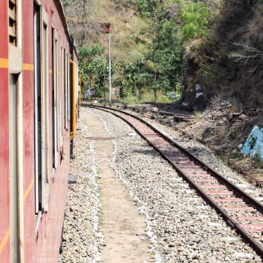 Oyuncak tren dağ yamaçlarında hareket ediyor, güzel bir manzara, bir dağ yamacı, bir vadi yamaçtan tepeye hareket ediyor, yeşil doğal ormanın arasında. Kalka 'dan Shimla' ya giden oyuncak tren Hindistan 'da.