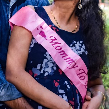 Hintli çift hamilelik çekimleri için poz veriyor. Çift yeşil çimenli bir çimenlikte poz veriyor ve kadın Hindistan, Yeni Delhi 'deki Lodhi Garden' da bebek çarpması yaşıyor.