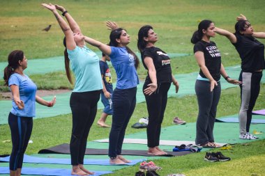 Yeni Delhi, Hindistan, 18 Haziran 2022 - Lodhi Garden 'da farklı yaşlarda insanlar için grup yoga sınıfı Surya Namashkar, Uluslararası Yoga Günü, parkta yoga dersine katılan büyük bir grup yetişkin