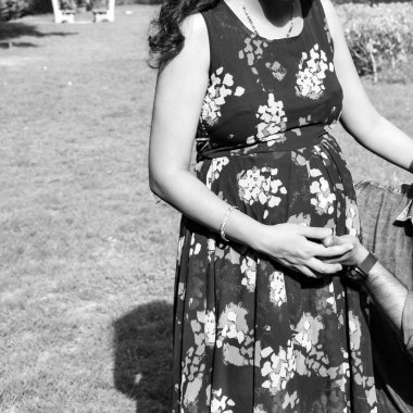 Hintli çift hamilelik çekimleri için poz veriyor. Çift yeşil çimenli bir çimenlikte poz veriyor ve kadın Yeni Delhi, Hindistan 'daki Lodhi Garden' da bebek çarpması yaşıyor.