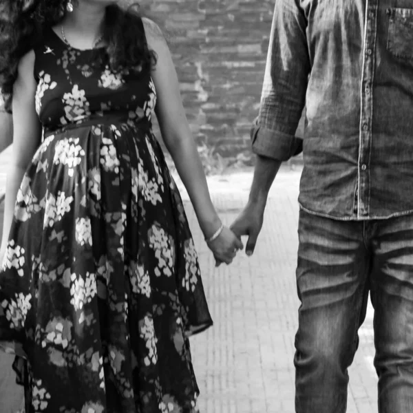 Indian couple posing for maternity baby shoot. The couple is posing in a lawn with green grass and the woman is falunting her baby bump in Lodhi Garden in New Delhi, India - Black and White