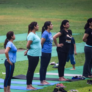 Yeni Delhi, Hindistan, 18 Haziran 2022 - Lodhi Garden 'da farklı yaşlarda insanlar için grup yoga sınıfı Surya Namaskar, Uluslararası Yoga Günü, parkta yoga dersine katılan büyük bir grup yetişkin