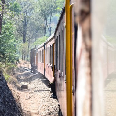 Oyuncak tren dağ yamaçlarında hareket ediyor, güzel bir manzara, bir dağ yamacı, bir vadi yamaçtan tepeye hareket ediyor, yeşil doğal ormanın arasında. Kalka 'dan Shimla' ya giden oyuncak tren Hindistan 'da.