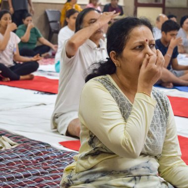 New Delhi, India, June 19 2022 -Group Yoga exercise session for people of different age groups in Balaji Temple, Vivek Vihar, International Yoga Day, Big group of adults attending yoga class in temple