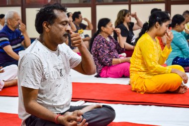 New Delhi, India, June 19 2022 -Group Yoga exercise session for people of different age groups in Balaji Temple, Vivek Vihar, International Yoga Day, Big group of adults attending yoga class in temple