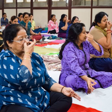 New Delhi, India, June 19 2022 -Group Yoga exercise session for people of different age groups in Balaji Temple, Vivek Vihar, International Yoga Day, Big group of adults attending yoga class in temple