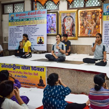 New Delhi, India, June 19 2022 -Group Yoga exercise session for people of different age groups in Balaji Temple, Vivek Vihar, International Yoga Day, Big group of adults attending yoga class in temple