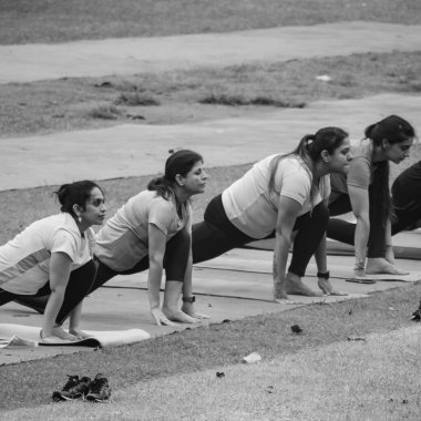 Delhi, Hindistan, 18 Haziran 2022 - Grup Yoga egzersiz sınıfı Surya Namaskar Lodhi Garden 'da farklı yaşlarda olanlar için. Uluslararası Yoga Günü, yoga sınıfına katılan büyük bir yetişkin grubu - Siyah ve Beyaz
