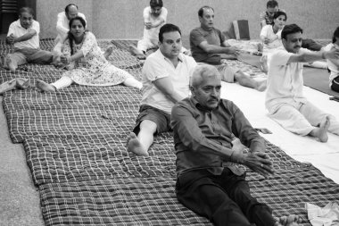 Delhi, India, June 19 2022-Group Yoga exercise session for people of different age groups in Balaji Temple,Vivek Vihar, International Yoga Day, Big group of adults attending yoga class-Black and White