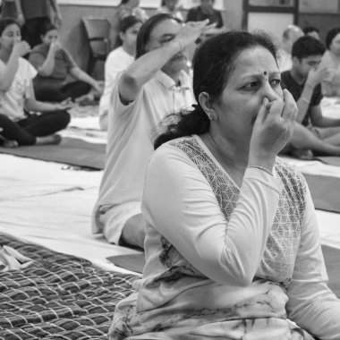 Delhi, India, June 19 2022-Group Yoga exercise session for people of different age groups in Balaji Temple,Vivek Vihar, International Yoga Day, Big group of adults attending yoga class-Black and White