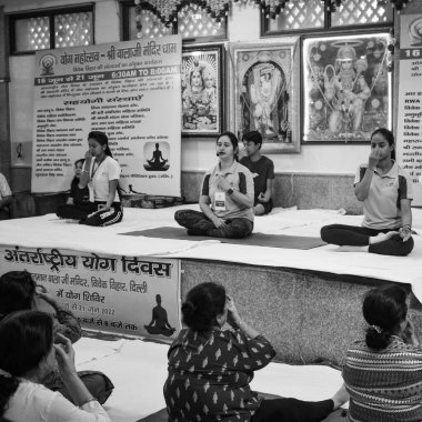 Delhi, India, June 19 2022-Group Yoga exercise session for people of different age groups in Balaji Temple,Vivek Vihar, International Yoga Day, Big group of adults attending yoga class-Black and White