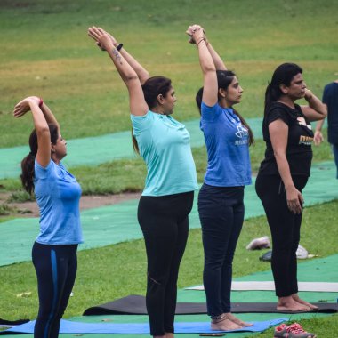 Yeni Delhi, Hindistan, 18 Haziran 2022 - Lodhi Garden 'da farklı yaşlarda insanlar için grup yoga sınıfı Surya Namaskar, Uluslararası Yoga Günü, parkta yoga dersine katılan büyük bir grup yetişkin