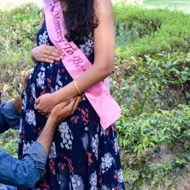 Hintli çift hamilelik çekimleri için poz veriyor. Çift yeşil çimenli bir çimenlikte poz veriyor ve kadın Hindistan, Yeni Delhi 'deki Lodhi Garden' da bebek çarpması yaşıyor.