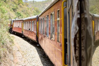 Oyuncak tren dağ yamaçlarında hareket ediyor, güzel bir manzara, bir dağ yamacı, bir vadi yamaçtan tepeye hareket ediyor, yeşil doğal ormanın arasında. Hindistan 'da Kalka' dan Shimla 'ya giden oyuncak tren, Hint treni.