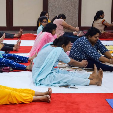 New Delhi, India, June 19 2022 -Group Yoga exercise session for people of different age groups in Balaji Temple, Vivek Vihar, International Yoga Day, Big group of adults attending yoga class in temple