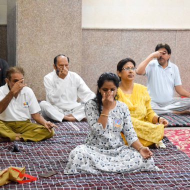 New Delhi, India, June 19 2022 -Group Yoga exercise session for people of different age groups in Balaji Temple, Vivek Vihar, International Yoga Day, Big group of adults attending yoga class in temple