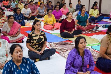 New Delhi, India, June 19 2022 -Group Yoga exercise session for people of different age groups in Balaji Temple, Vivek Vihar, International Yoga Day, Big group of adults attending yoga class in temple