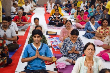 New Delhi, India, June 19 2022 -Group Yoga exercise session for people of different age groups in Balaji Temple, Vivek Vihar, International Yoga Day, Big group of adults attending yoga class in temple