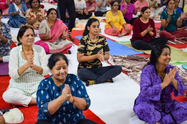 New Delhi, India, June 19 2022 -Group Yoga exercise session for people of different age groups in Balaji Temple, Vivek Vihar, International Yoga Day, Big group of adults attending yoga class in temple