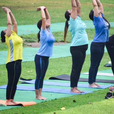 Yeni Delhi, Hindistan, 18 Haziran 2022 - Lodhi Garden 'da farklı yaşlarda insanlar için grup yoga sınıfı Surya Namaskar, Uluslararası Yoga Günü, parkta yoga dersine katılan büyük bir grup yetişkin