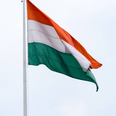 India flag flying high at Connaught Place with pride in blue sky, India flag fluttering, Indian Flag on Independence Day and Republic Day of India, tilt up shot, Waving Indian flag, Har Ghar Tiranga