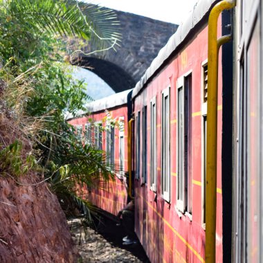 Oyuncak tren dağ yamaçlarında hareket ediyor, güzel bir manzara, bir dağ yamacı, bir vadi yamaçtan tepeye hareket ediyor, yeşil doğal ormanın arasında. Hindistan 'da Kalka' dan Shimla 'ya giden oyuncak tren, Hint treni.