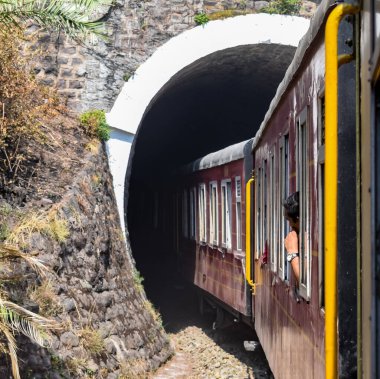 Oyuncak tren dağ yamaçlarında hareket ediyor, güzel bir manzara, bir dağ yamacı, bir vadi yamaçtan tepeye hareket ediyor, yeşil doğal ormanın arasında. Hindistan 'da Kalka' dan Shimla 'ya giden oyuncak tren, Hint treni.