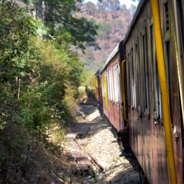 Oyuncak tren dağ yamaçlarında hareket ediyor, güzel bir manzara, bir dağ yamacı, bir vadi yamaçtan tepeye hareket ediyor, yeşil doğal ormanın arasında. Hindistan 'da Kalka' dan Shimla 'ya giden oyuncak tren, Hint treni.