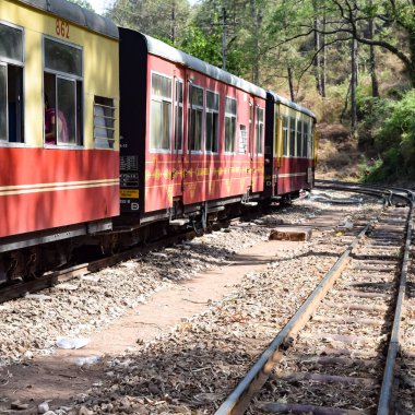 Oyuncak tren dağ yamaçlarında hareket ediyor, güzel bir manzara, bir dağ yamacı, bir vadi yamaçtan tepeye hareket ediyor, yeşil doğal ormanın arasında. Hindistan 'da Kalka' dan Shimla 'ya giden oyuncak tren, Hint treni.
