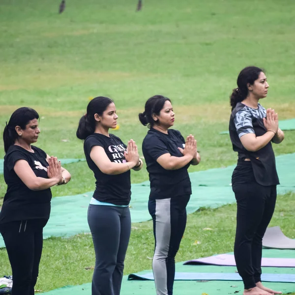 Yeni Delhi, Hindistan, 18 Haziran 2022 - Lodhi Garden 'da farklı yaşlarda insanlar için grup yoga sınıfı Surya Namaskar, Uluslararası Yoga Günü, parkta yoga dersine katılan büyük bir grup yetişkin