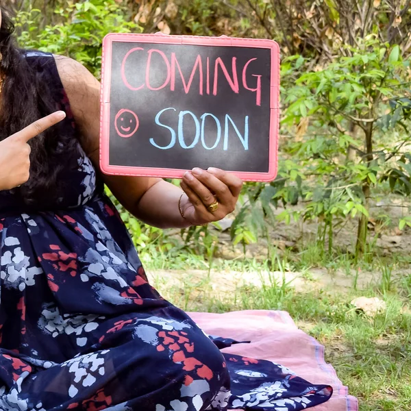 Indian couple posing for maternity baby shoot. The couple is posing in a lawn with green grass and the woman is falunting her baby bump in Lodhi Garden in New Delhi, India